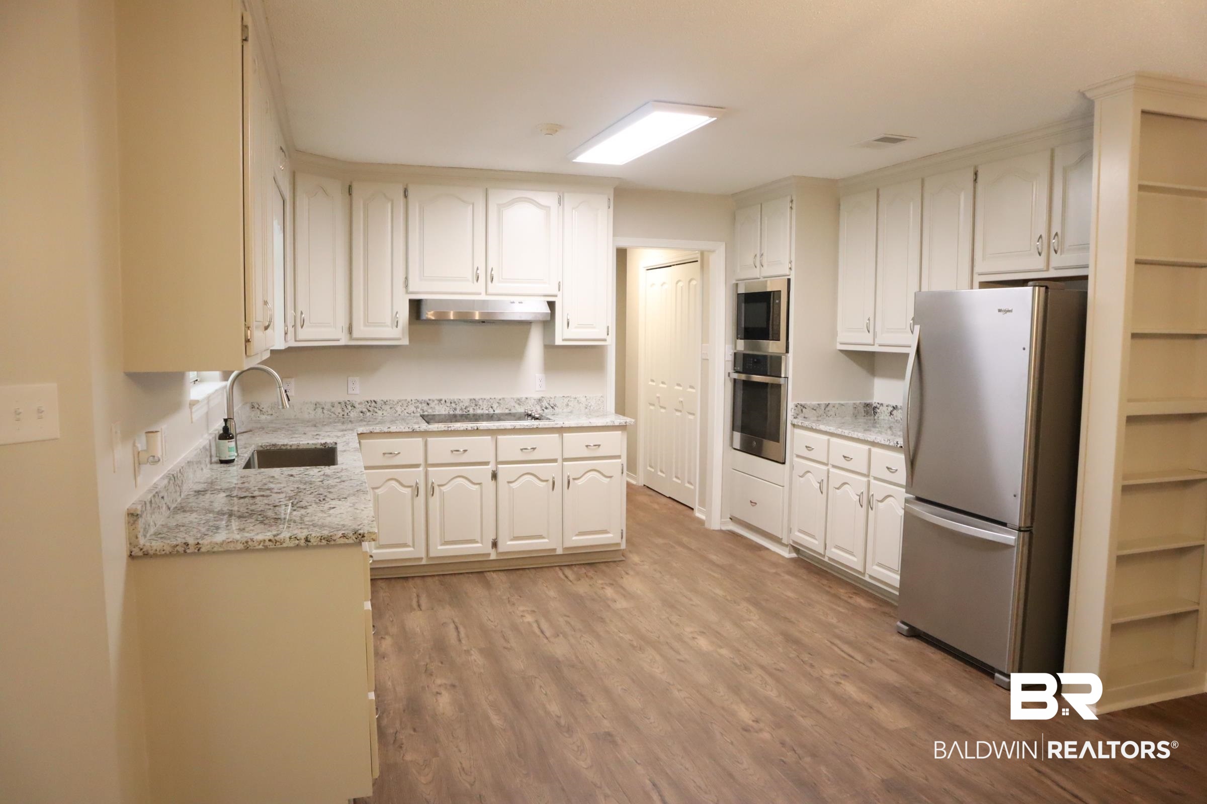 12150 Lee Bishop Road Irvington, AL 36544 - Photo 10 of 26 Kitchen featuring wood finished floors, a sink, under cabinet range hood, and stainless steel appliances