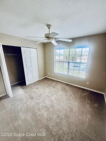 an empty room with windows and ceiling fan view