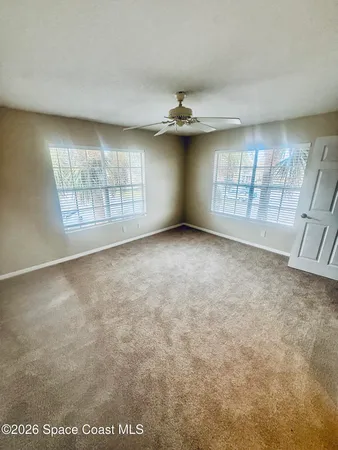an empty room with windows and ceiling fan