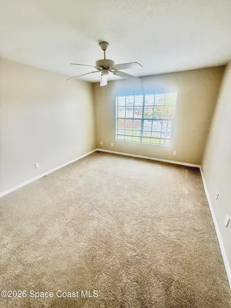 an empty room with windows and fan