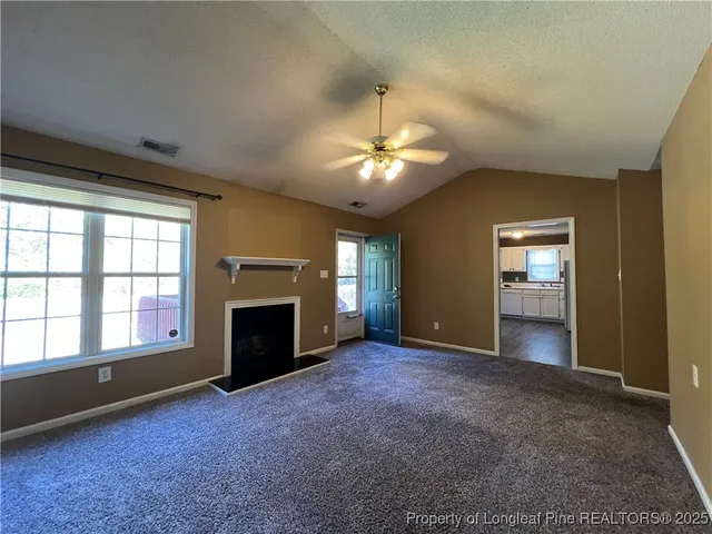 an empty room with windows and fireplace