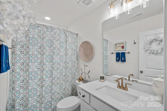 a bathroom with a granite countertop toilet sink mirror and vanity