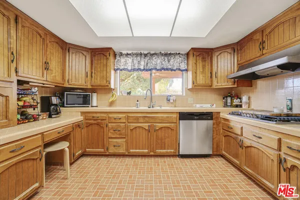 a kitchen with stainless steel appliances granite countertop a sink a stove a refrigerator cabinets and a window