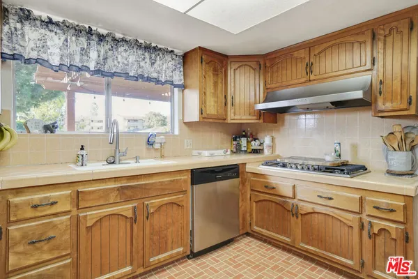 a kitchen with cabinets stainless steel appliances a sink and a window