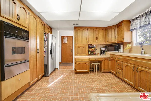 a kitchen with stainless steel appliances a sink a stove a refrigerator cabinets and dining table