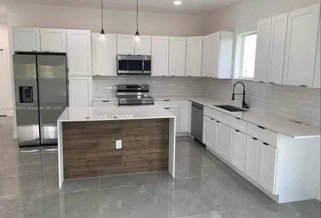 a kitchen with a sink cabinets stainless steel appliances and a window