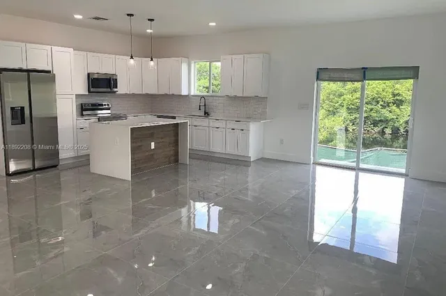 a large kitchen with stainless steel appliances granite countertop a stove a sink and a refrigerator