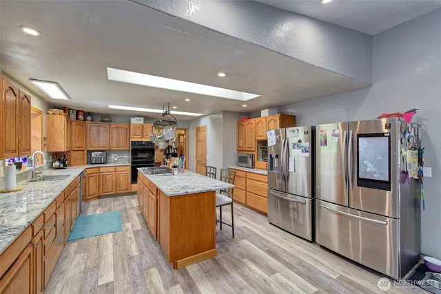 a kitchen with stainless steel appliances granite countertop a refrigerator a sink dishwasher a stove and a refrigerator