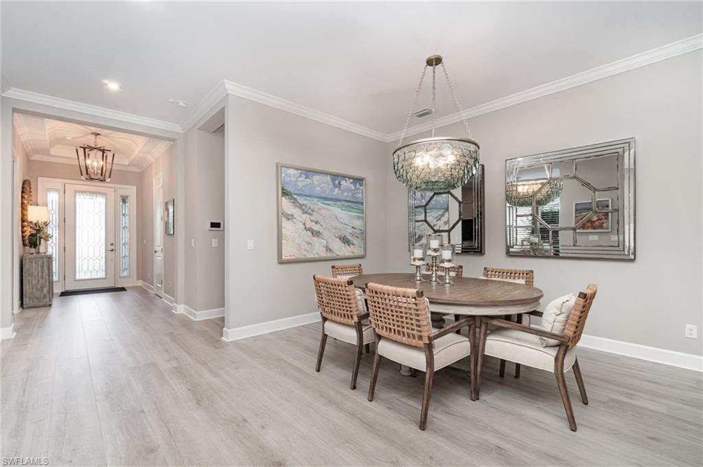 9536 Montelanico Loop Naples, FL 34119 - Photo 7 of 24 a dining room with wooden floor a chandelier a wooden table and chairs