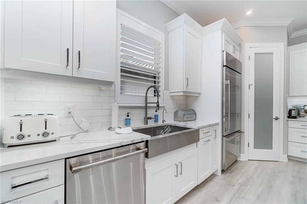 9536 Montelanico Loop Naples, FL 34119 - Photo 9 of 24 a kitchen with stainless steel appliances granite countertop a sink stove and refrigerator