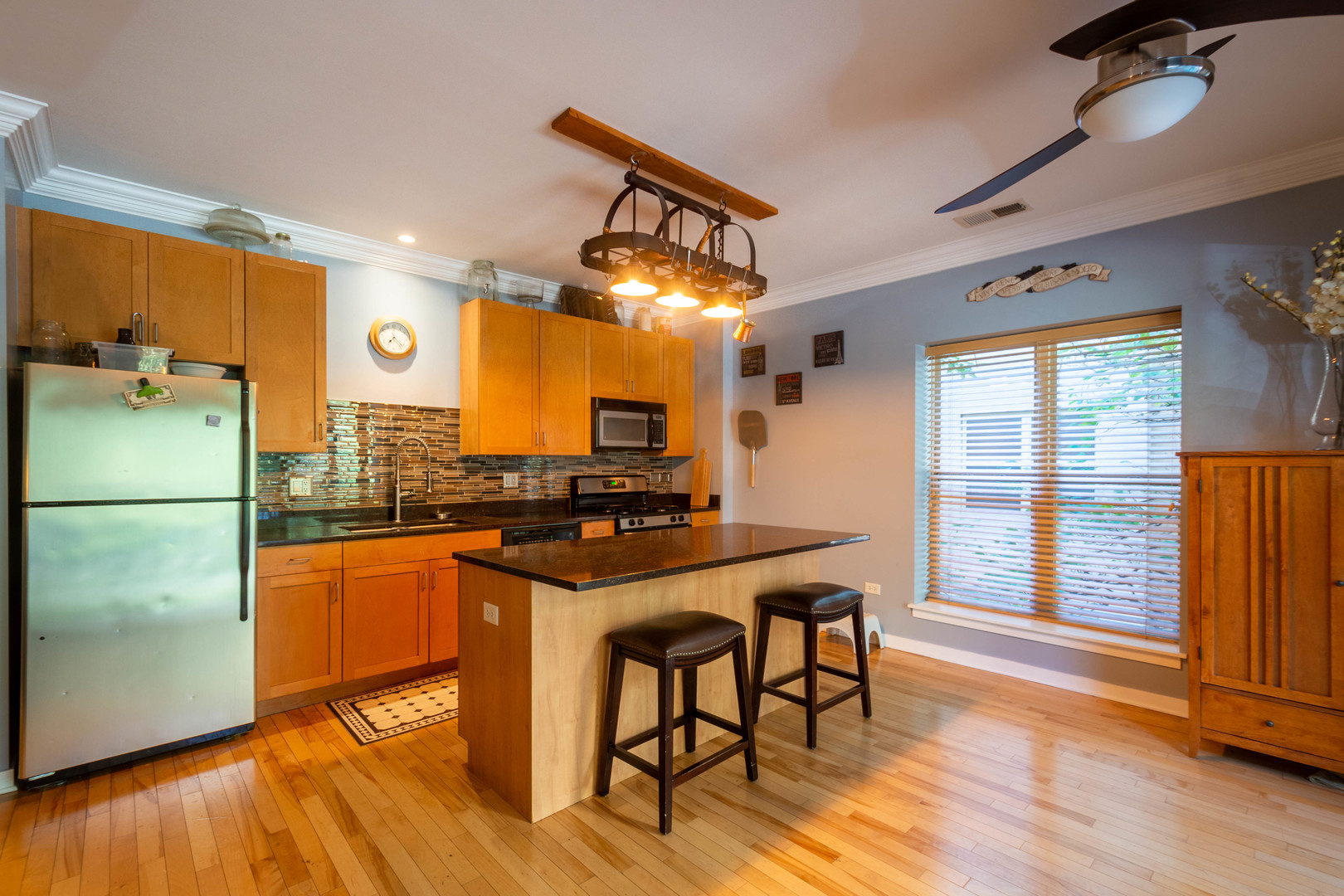 1075 West Roosevelt Road, Unit 201 Chicago, IL 60608 - Photo 4 of 21 a kitchen with stainless steel appliances granite countertop a refrigerator a sink dishwasher a stove and a dining table with wooden floor