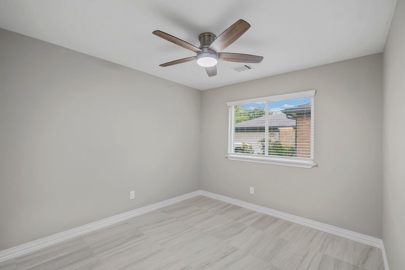 16519 Gaeldom Drive Houston, TX 77084 - Photo 22 of 28 an empty room with wooden floor ceiling fan and windows