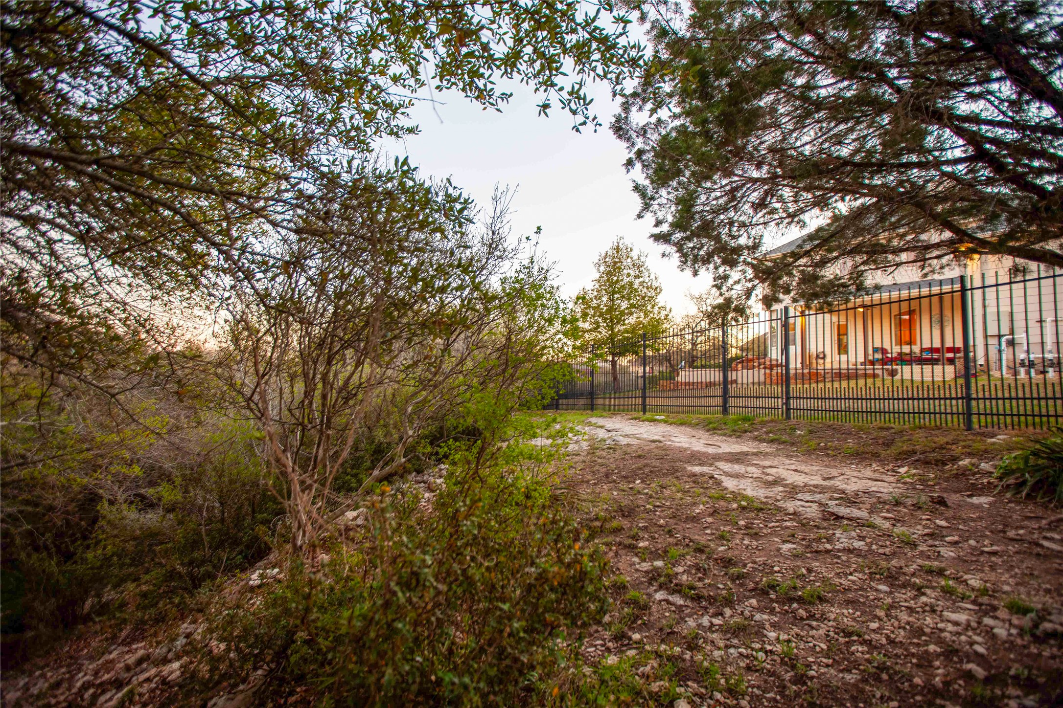 1432 Tom Sawyer Road Austin, TX 78737 - Photo 30 of 33 A private driveway leads to a charming residence, secured by an elegant iron fence.