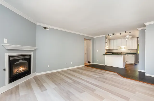 a view of an empty room with kitchen and fireplace