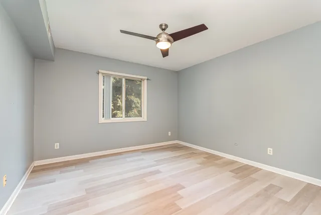 a view of empty room with wooden floor and fan