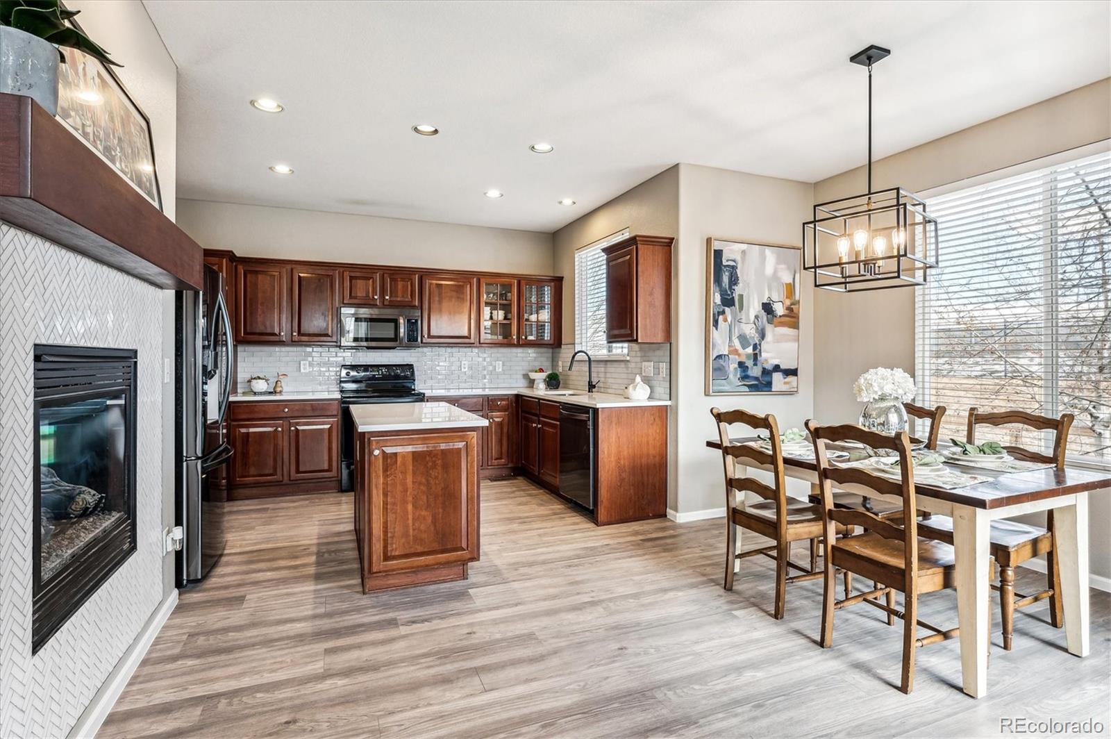 10904 Brooklawn Road Highlands Ranch, CO 80130 - Photo 7 of 50 a kitchen with stainless steel appliances granite countertop a stove top oven a sink dishwasher a dining table and chairs with wooden floor