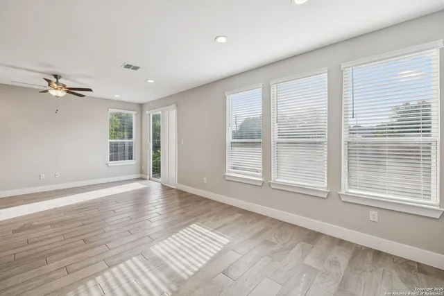 a view of an empty room with a window and wooden floor