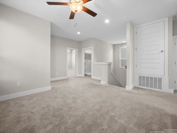 an empty room with chandelier fan and windows