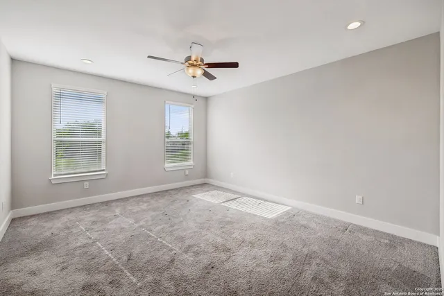 an empty room with windows and fan