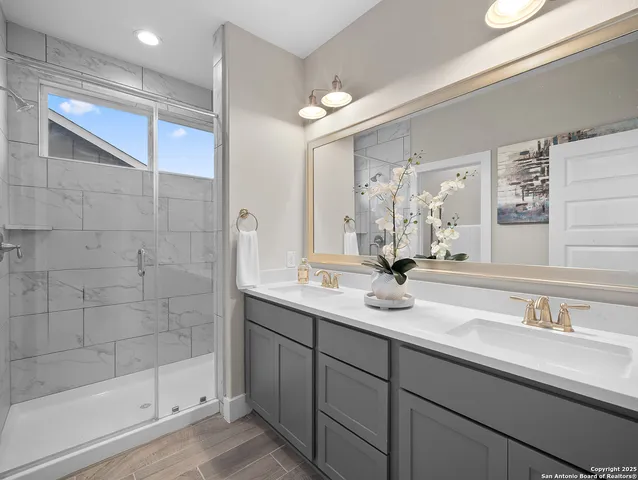 a bathroom with a double vanity sink mirror and shower