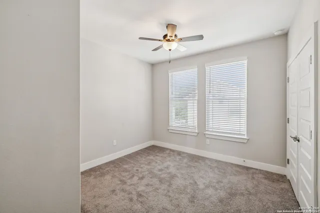 an empty room with windows and fan