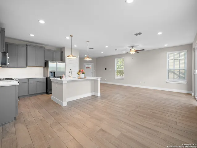 a large white kitchen with kitchen island a sink dishwasher a stove a refrigerator and white cabinets with wooden floor