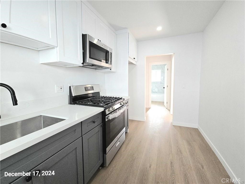 11171 Bullis Road Lynwood, CA 90262 - Photo 9 of 15 a kitchen with stainless steel appliances granite countertop a sink and a stove top oven with wooden floor