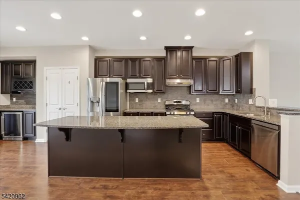 a large kitchen with stainless steel appliances granite countertop a stove a sink dishwasher a refrigerator and a oven with large countertops