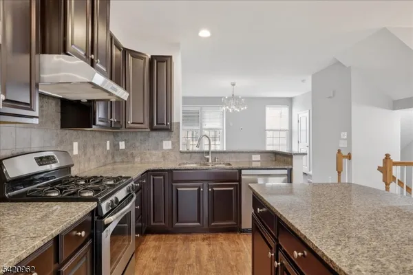 a kitchen with stainless steel appliances granite countertop a sink stove and cabinets