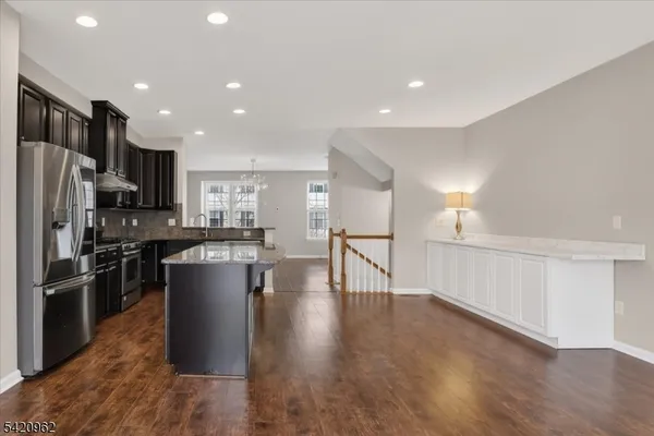 a kitchen with stainless steel appliances kitchen island granite countertop a refrigerator a stove a sink and a microwave with wooden floor