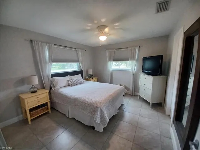 a spacious bedroom with a bed and a flat tv screen on a dresser