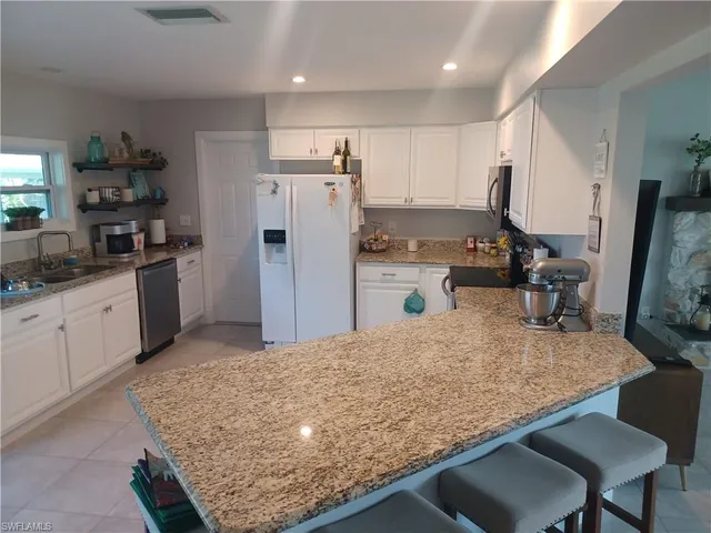 a kitchen with refrigerator and chairs