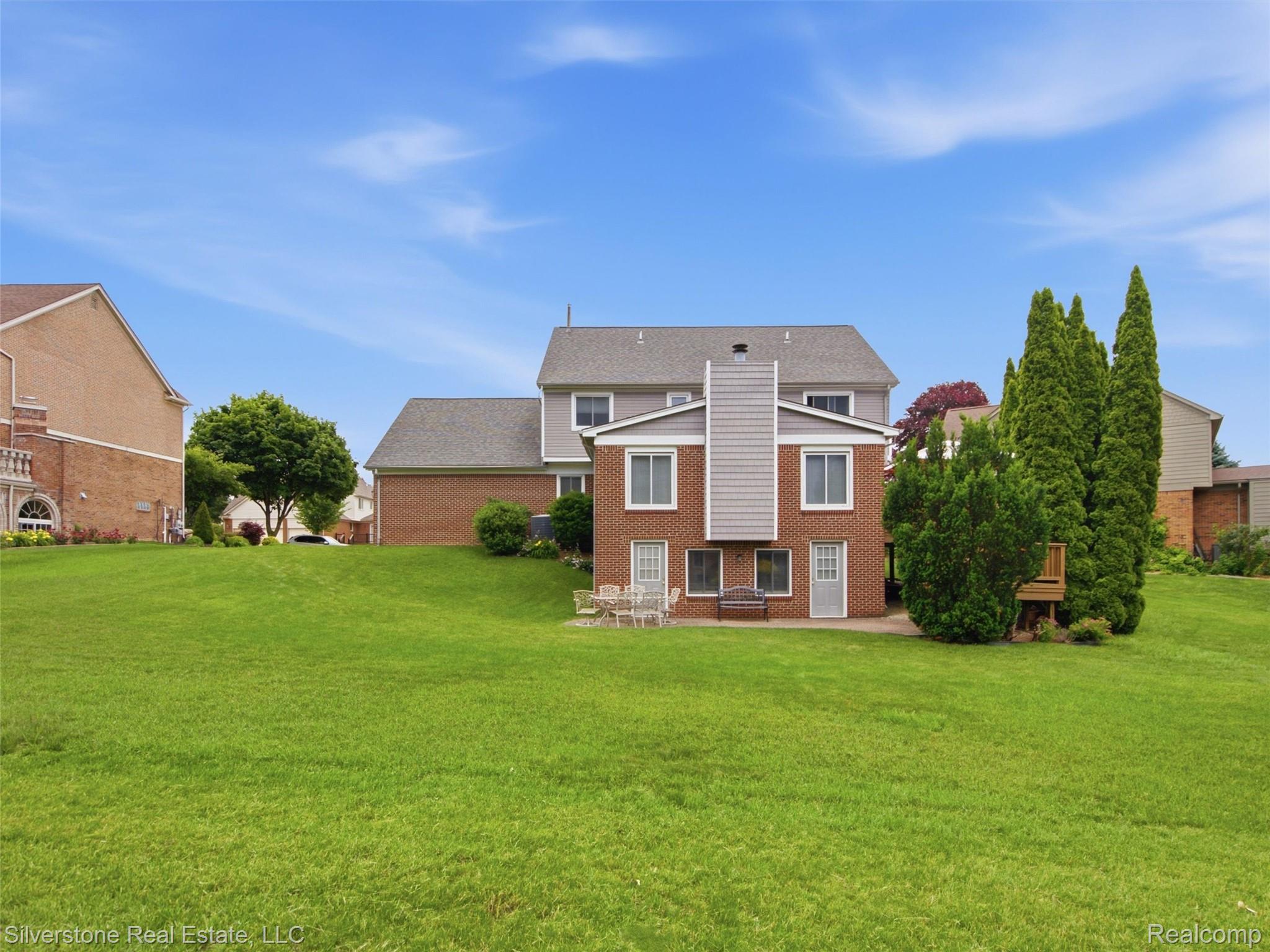 6577 Edith Court Troy, MI 48085 - Photo 53 of 61 Expansive green lawn surrounds the rear of the property, featuring a multi-level structure with brick and siding exteriors