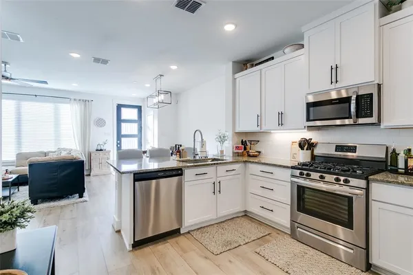 a kitchen with stainless steel appliances white cabinets white refrigerator and a stove top oven