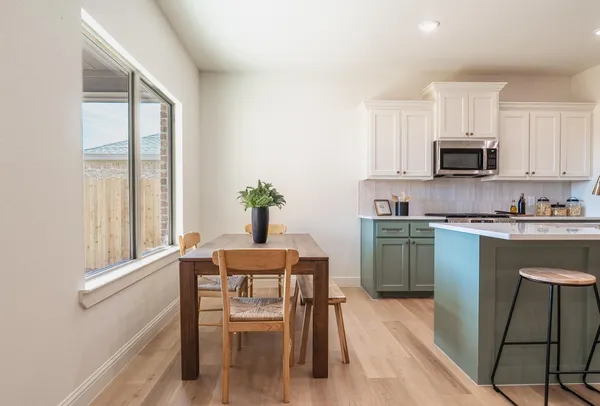 a kitchen with granite countertop a stove a sink a microwave a dining table and chairs