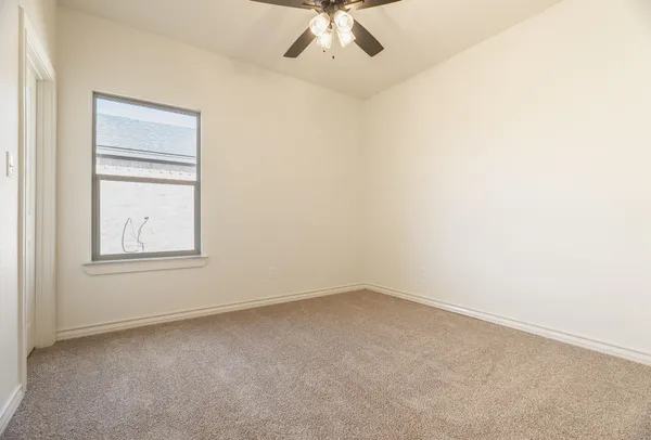 an empty room with a chandelier fan and windows