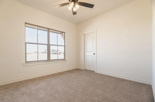 an empty room with chandelier fan and windows