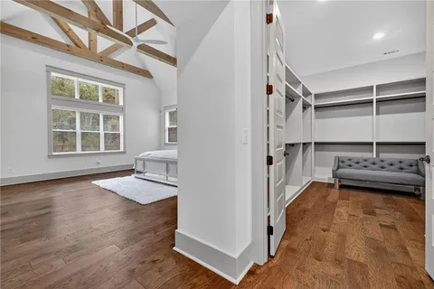 a spacious bedroom with a bed a dresser and a chandelier