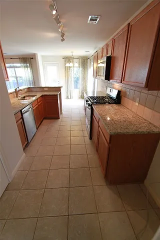 a large kitchen with a stove a sink dishwasher and a refrigerator