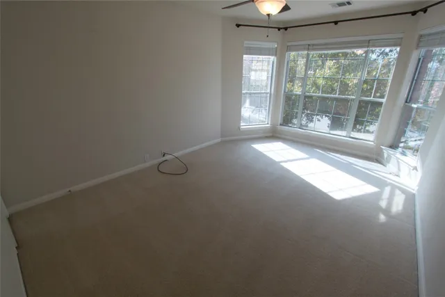 a view of an empty room and chandelier fan