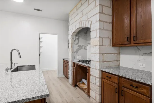 a kitchen with stainless steel appliances granite countertop a sink a stove and a wooden floors