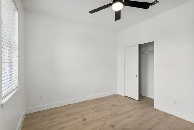 an empty room with a ceiling fan and wooden floor