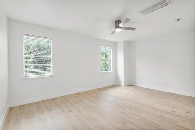 an empty room with windows and ceiling fan