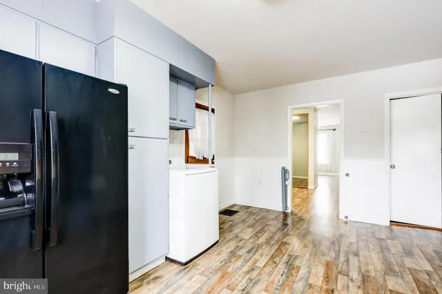a kitchen with a refrigerator and a wooden floor
