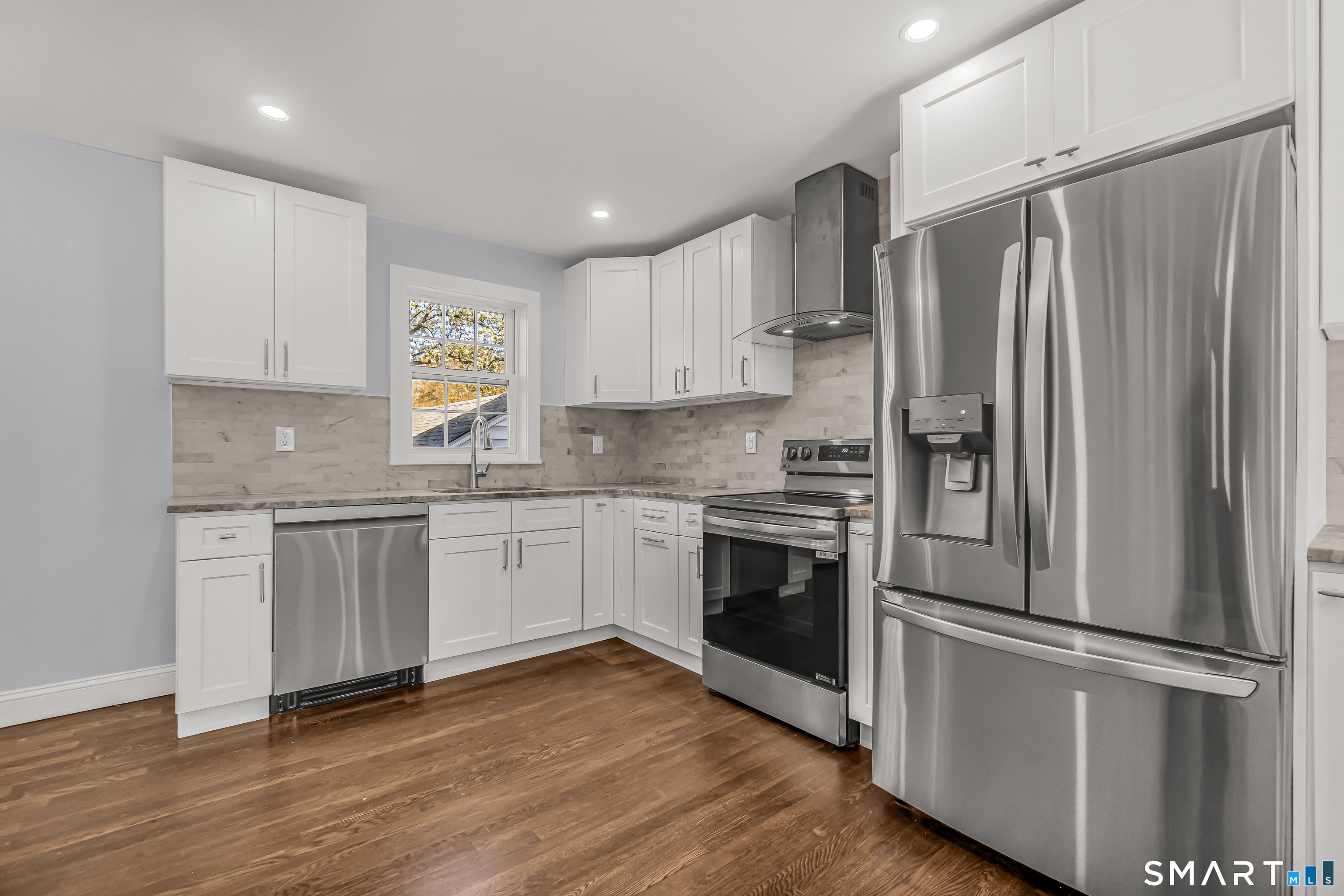 1770 Stratfield Road Fairfield, CT 06825 - Photo 14 of 40 a kitchen with a refrigerator stainless steel appliances wooden floor and cabinets