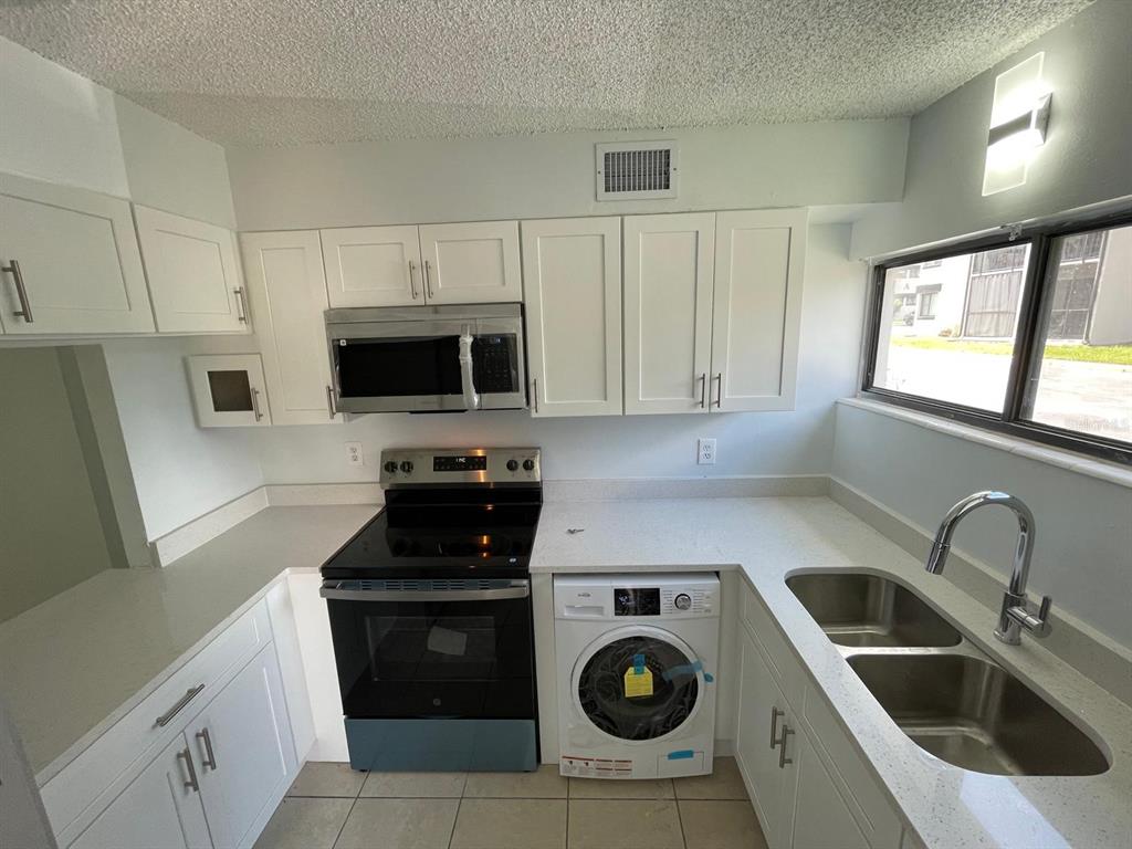 1108 Bartow Road, Unit D37 Lakeland, FL 33801 - Photo 4 of 16 a kitchen with a sink a stove a microwave and cabinets