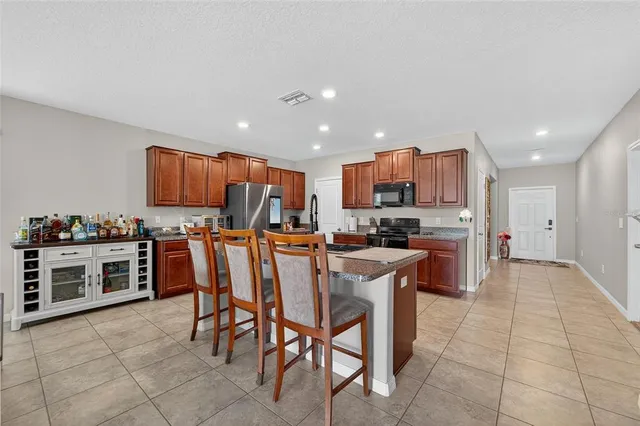 a kitchen with stainless steel appliances granite countertop a stove top oven a sink dishwasher and a refrigerator with cabinets