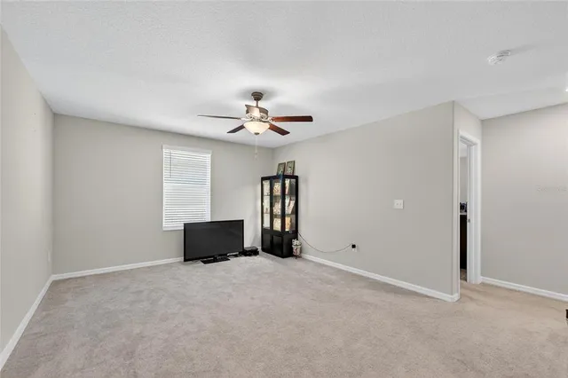 a view of an empty room with chandelier fan