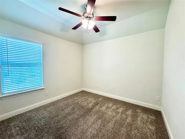 an empty room with a window and a ceiling fan