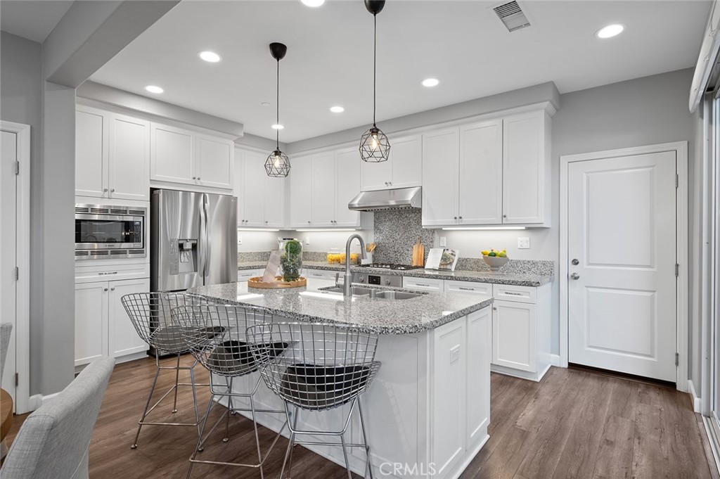 84 Granite Path Irvine, CA 92620 - Photo 13 of 55 a kitchen with stainless steel appliances granite countertop a refrigerator a sink dishwasher a stove and white cabinets with wooden floor
